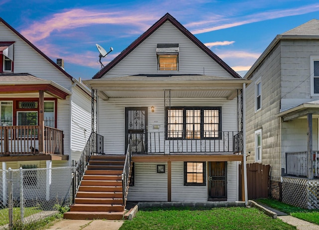 view of front facade featuring covered porch, fence, and stairs