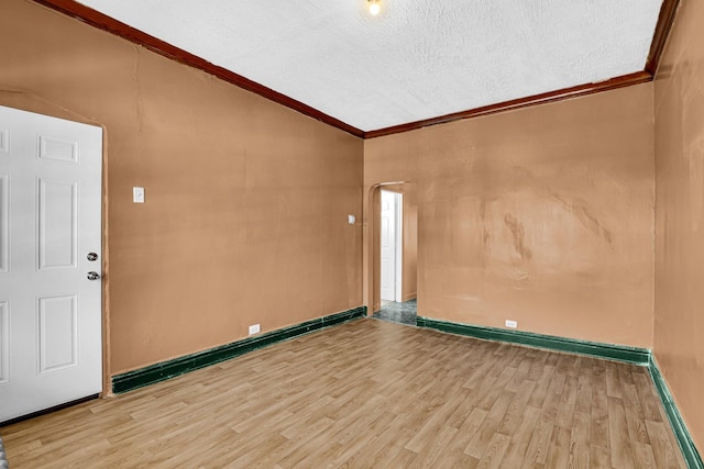 unfurnished room with a textured ceiling, baseboards, crown molding, and wood finished floors