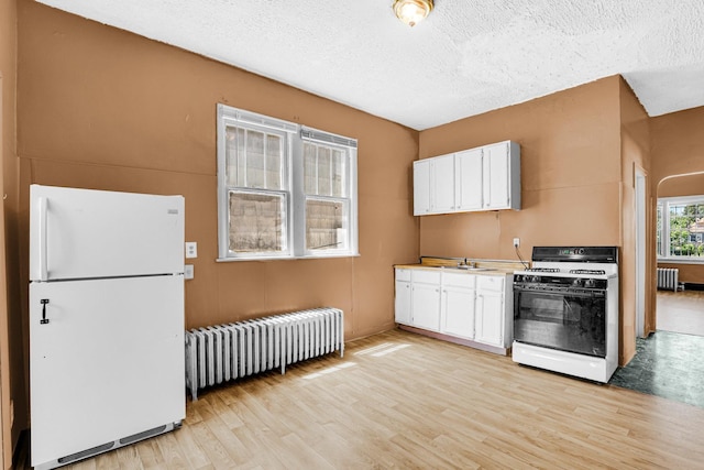 kitchen featuring white appliances, white cabinetry, light wood finished floors, and radiator heating unit