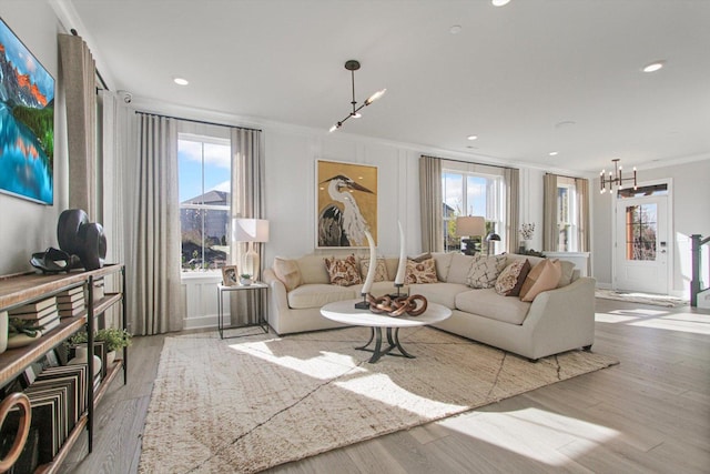 living room featuring ornamental molding, recessed lighting, wood finished floors, and a notable chandelier