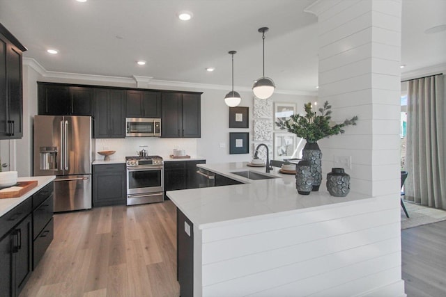 kitchen with stainless steel appliances, ornamental molding, light wood-type flooring, and a sink