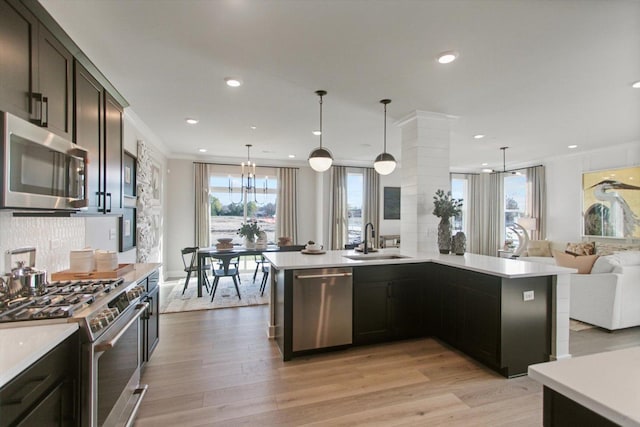 kitchen with open floor plan, light countertops, appliances with stainless steel finishes, and a sink