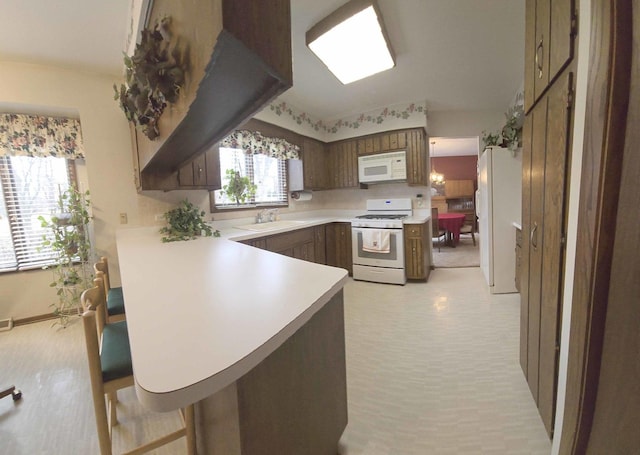 kitchen featuring white appliances, a peninsula, light countertops, and a sink