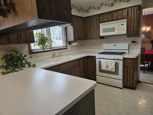 kitchen with white appliances, a notable chandelier, light countertops, and a sink