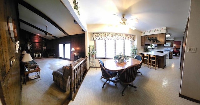 dining space with lofted ceiling with beams, a ceiling fan, wood walls, and a wealth of natural light