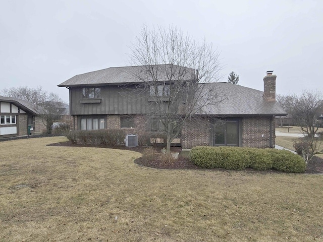 back of property with roof with shingles, a yard, a chimney, central air condition unit, and brick siding