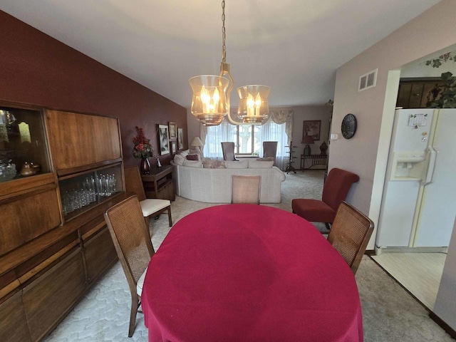 dining area featuring visible vents, lofted ceiling, light carpet, and an inviting chandelier