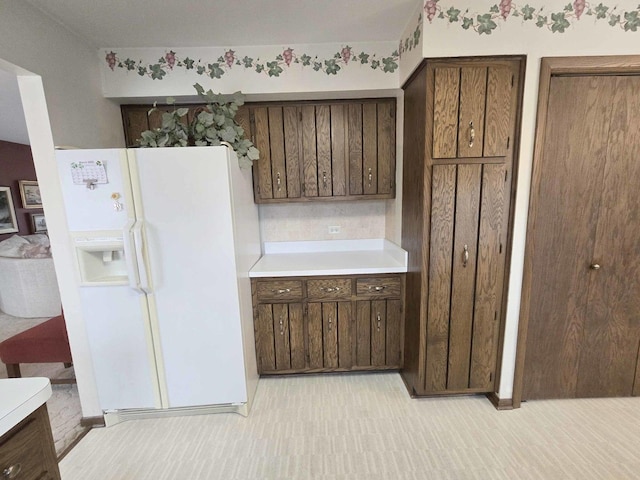 kitchen with light countertops, dark brown cabinets, and white fridge with ice dispenser