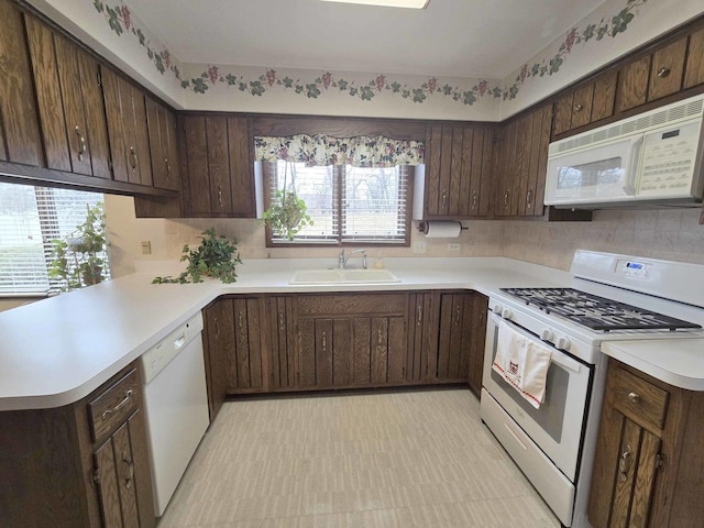 kitchen featuring white appliances, light floors, a sink, light countertops, and dark brown cabinets