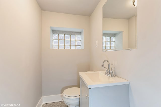 half bath with toilet, vanity, and baseboards