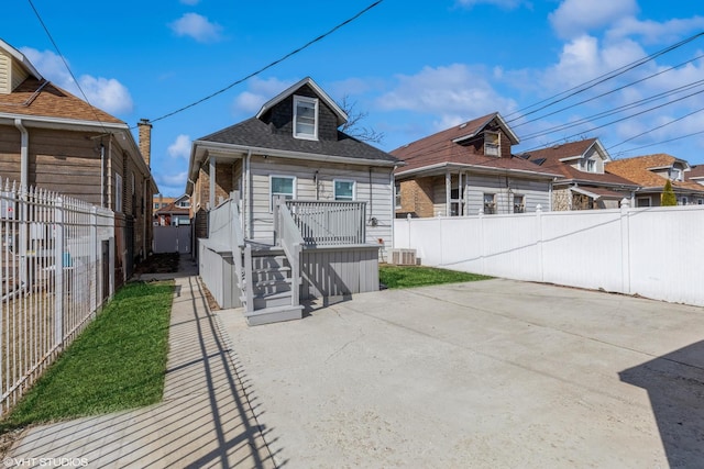 back of house with a shingled roof, central AC unit, a fenced backyard, and a patio area