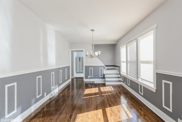 unfurnished dining area featuring visible vents, baseboards, a notable chandelier, and dark wood-style flooring