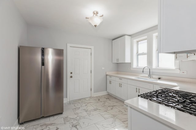 kitchen featuring light countertops, freestanding refrigerator, marble finish floor, white cabinetry, and a sink