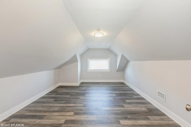 bonus room featuring dark wood-type flooring, visible vents, baseboards, and lofted ceiling