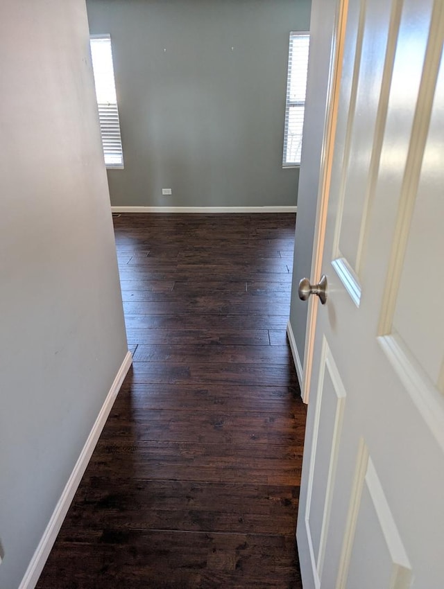 spare room with dark wood-type flooring and baseboards