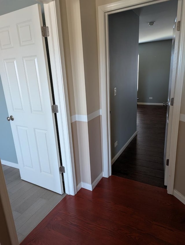 hallway featuring baseboards and dark wood finished floors