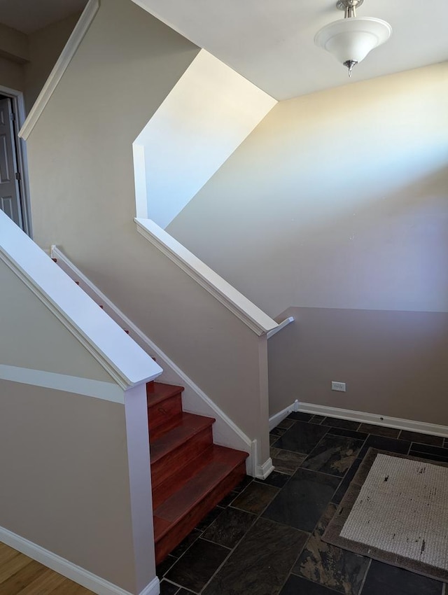 stairway with stone finish floor and baseboards