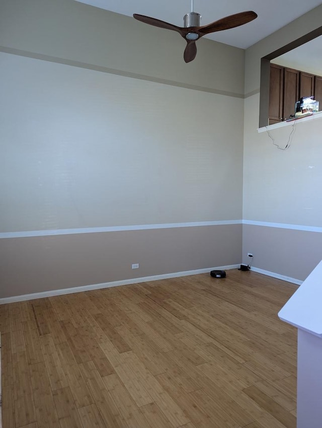 clothes washing area with baseboards, ceiling fan, and light wood finished floors