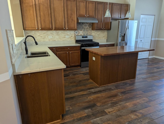 kitchen with under cabinet range hood, stainless steel appliances, dark wood-type flooring, a sink, and decorative backsplash