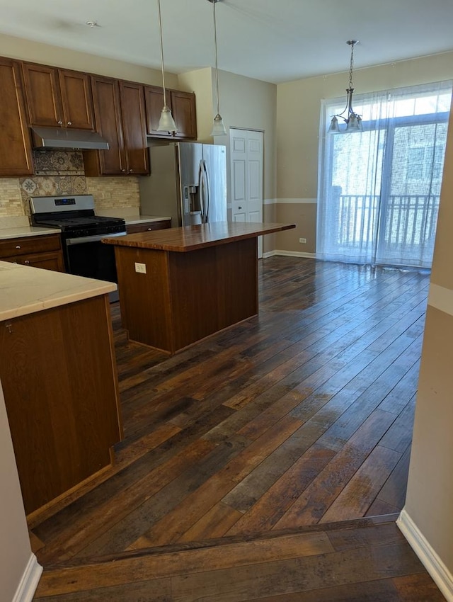 kitchen with dark wood-style flooring, stainless steel appliances, decorative backsplash, a kitchen island, and under cabinet range hood