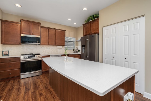 kitchen featuring dark wood finished floors, light countertops, decorative backsplash, and stainless steel appliances