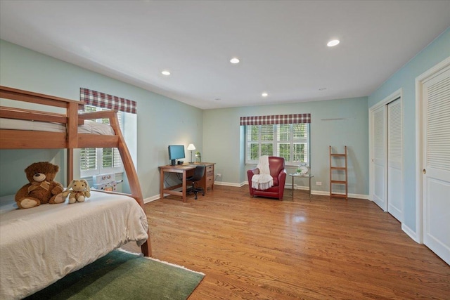 bedroom featuring recessed lighting, baseboards, multiple closets, and wood finished floors