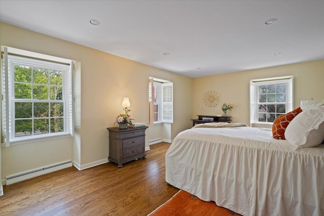 bedroom featuring wood finished floors, baseboards, a baseboard radiator, recessed lighting, and baseboard heating