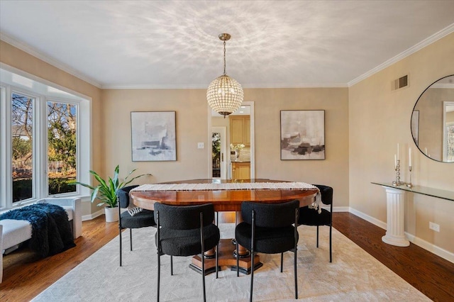 dining area with visible vents, baseboards, wood finished floors, and ornamental molding