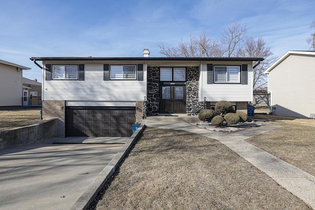 split foyer home with a garage, brick siding, and driveway