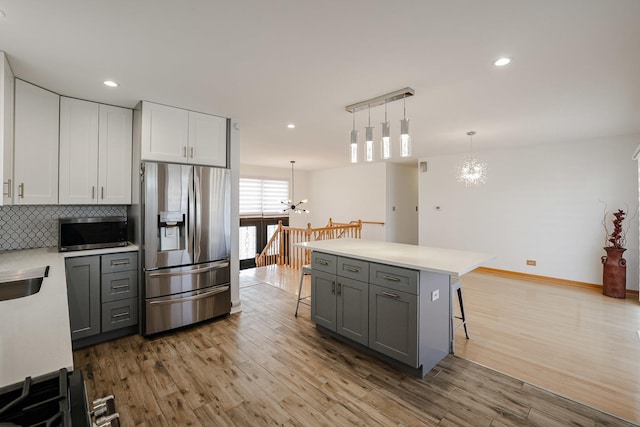 kitchen with a breakfast bar, light wood-style flooring, gray cabinetry, and stainless steel appliances