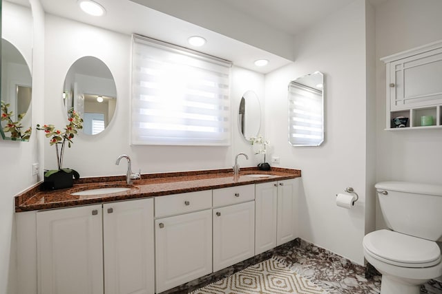 bathroom featuring double vanity, toilet, recessed lighting, and a sink