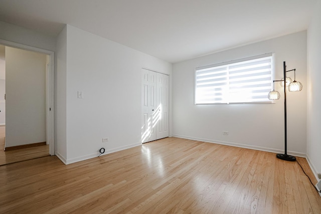 unfurnished bedroom featuring a closet, baseboards, and light wood-style flooring