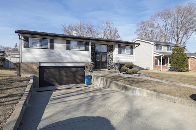 raised ranch with an attached garage, brick siding, and driveway