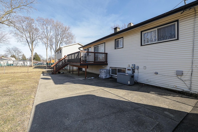 exterior space with a wooden deck, a yard, a chimney, stairs, and central air condition unit