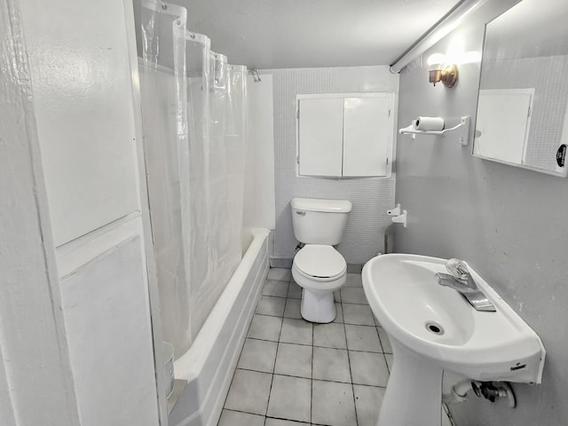 bathroom with toilet, tile patterned flooring, a sink, and shower / tub combo with curtain