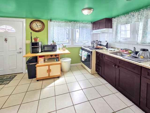 kitchen with tasteful backsplash, gas range oven, light countertops, under cabinet range hood, and black microwave