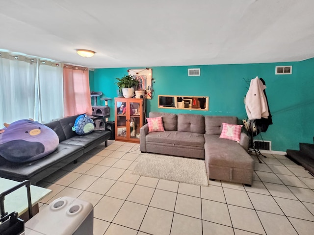 living room with stairs, visible vents, and light tile patterned floors