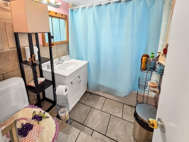 full bath with tile patterned flooring, tile walls, and vanity