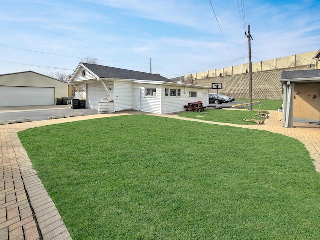 ranch-style home featuring a garage, a shingled roof, an outbuilding, fence, and a front lawn