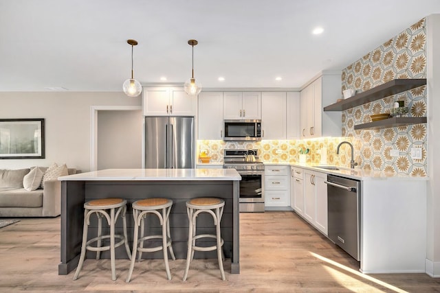 kitchen with a sink, light countertops, appliances with stainless steel finishes, decorative backsplash, and open shelves