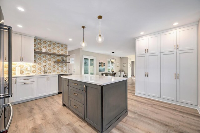 kitchen featuring wallpapered walls, a sink, light wood finished floors, and open shelves