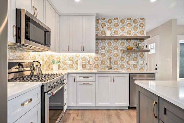 kitchen featuring decorative backsplash, stainless steel appliances, light countertops, open shelves, and a sink