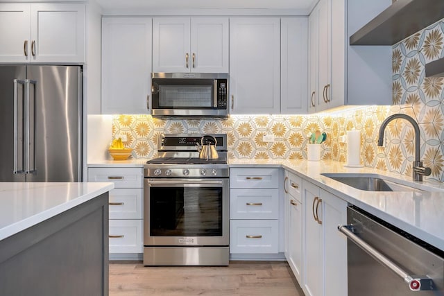 kitchen with light countertops, light wood-style flooring, decorative backsplash, appliances with stainless steel finishes, and a sink