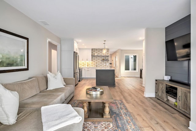 living area featuring baseboards, visible vents, and light wood-style floors