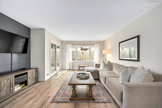 living area featuring baseboards, visible vents, and light wood finished floors