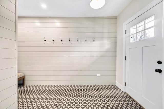 mudroom with wooden walls and tile patterned floors