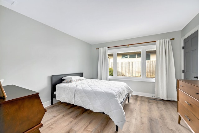 bedroom featuring light wood-style floors, visible vents, and baseboards