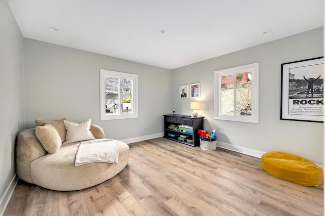 sitting room featuring baseboards, wood finished floors, and a healthy amount of sunlight