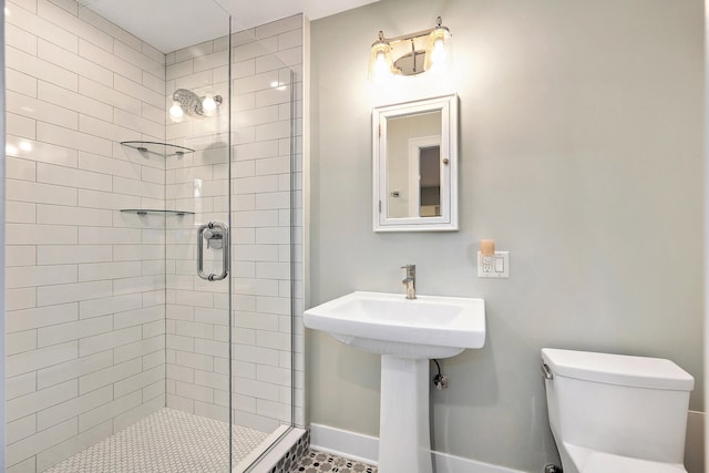 bathroom featuring baseboards, a sink, a shower stall, and toilet