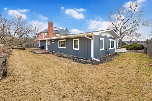 view of side of property featuring a chimney, fence, and a yard